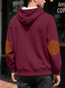 Détail du sweat à capuche bordeaux avec coudières marron et texture jacquard en losanges