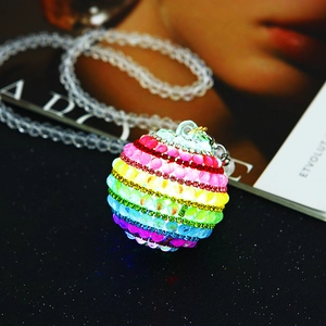 Detail of glowing rainbow crystal car charm with colorful rhinestones on dark background