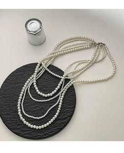 Elegant multi-layer pearl necklace with white beads on black textured tray