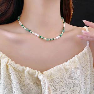 Detail of malachite and pearl necklace on model's neck for elegant styling