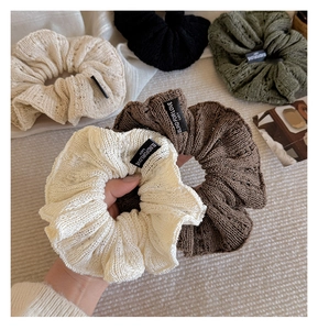 Close-up of knit fabric texture and logo tag on these elegant ruffled scrunchies
