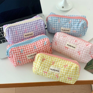 Detailed overhead view of five colorful quilted plaid cosmetic bags on a white desk