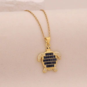 Macro detail of golden turtle pendant featuring blue rectangular stone and sparkling gems