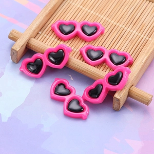 Close-up of five pink heart-shaped resin charms with black lenses for DIY crafts