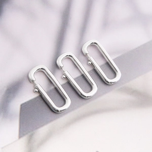 Three silver oval spring ring clasps for DIY jewelry making on white marble background