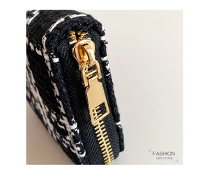 Close-up of golden zipper on black and white houndstooth fabric lady's purse