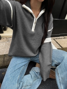 Detail of grey half-zip knit sweater with white striped collar and cuffs in natural light