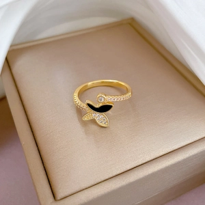 Macro shot of gold butterfly ring with black enamel and zircons on champagne velvet box
