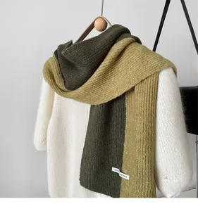 Close-up of thick color-block knit scarf in dark green and mustard yellow wool