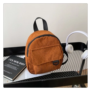 Detailed close-up of brown corduroy mini backpack with front flap pocket on a mesh cart