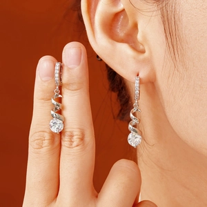 Detailed close-up of sparkling zircon drop earrings with elegant silver spiral design