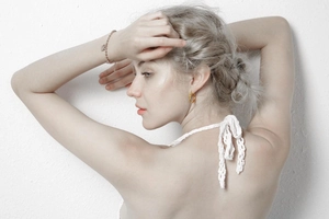 Close-up of elegant gold knot earrings and heart pendant bracelet on a model