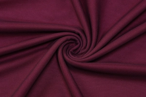 Détail macro du tissu en maille rouge vin montrant la texture et les plis souples