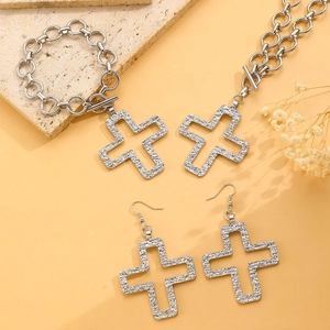 Macro detail of silver cross jewelry set with textured pendant on necklace and bracelet