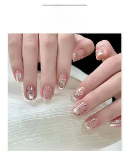 Details von kurzen quadratischen Kunstnägeln mit Schleife, Strass und schwarzem Punkt-Cat-Eye