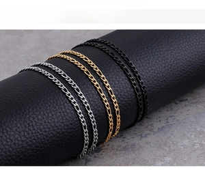 Detail of Figaro style chains in gold, silver, and black finish on a leather display