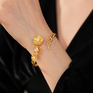 Detail of vintage gold flower cuff bracelet with sparkling zircon and white pearls