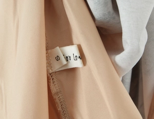 Detail of white fabric inner label s For Love on elegant beige floral silk dress