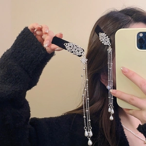 Detailed view of silver hair clip with sparkling rhinestones and long pearl tassels