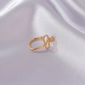 Chic punk style gold U-shaped non-pierced nose ring on elegant purple silk fabric