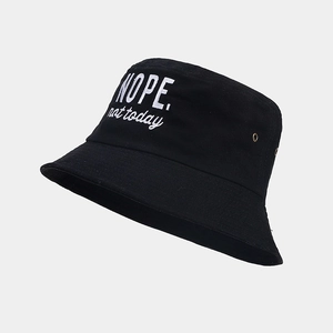 Detail of embroidered 'NOPE.' text on breathable black cotton bucket hat with eyelets