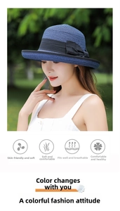 Outdoor shot of a woman wearing a blue foldable straw sun hat with a black bow detail