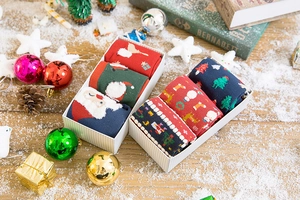 Detail of Christmas themed crew socks in white polka dot gift boxes on a snowy background
