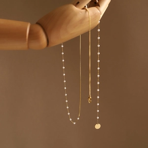 Double layered gold pearl necklace with a minimalist round pendant on a wooden display