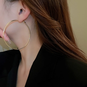 Model wearing large minimalist golden hoop earrings with a sleek polished finish