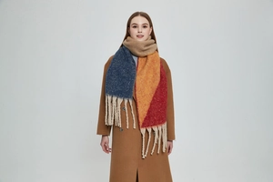 Detail shot of multi-color thick knit scarf with long tassels on a model in studio