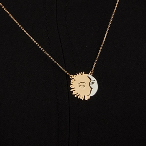 Minimalist sun and moon pendant necklace with gold and silver finish on black fabric