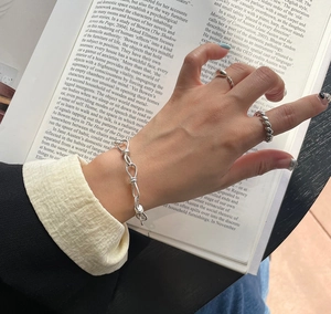 Detail of 925 sterling silver rope bracelet and minimalist twist rings on hands