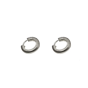 Gros plan détaillé sur des boucles d'oreilles créoles argentées à texture torsadée