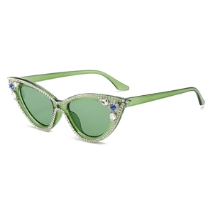 Translucent green cat eye sunglasses with rhinestones and blue crystals on white background