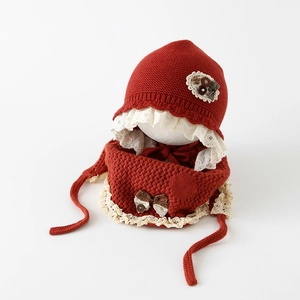Détail de l'ensemble bonnet et écharpe en tricot rouge pour bébé avec dentelle blanche