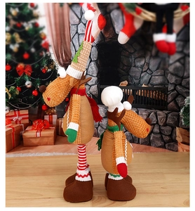Detail of Christmas reindeer plush decorations with striped legs near fireplace