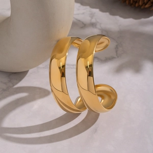 Close-up of polished 18K gold-plated double-layer open bangle on marble surface