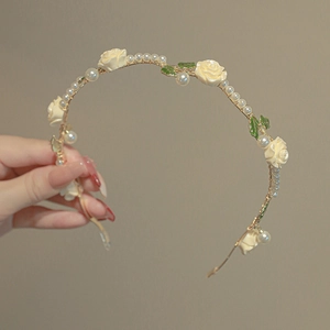 Detail view of a vintage floral headband featuring cream roses and elegant pearls