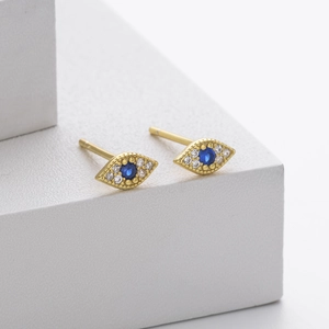 Detail shot of gold evil eye stud earrings with blue gemstone and white zircon stones