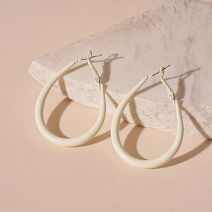 Detail of cream drop-shaped earrings with matte finish on natural stone display