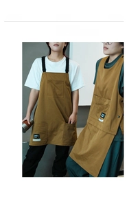 Detail of tan canvas work aprons featuring heavy-duty pockets and reinforced stitching