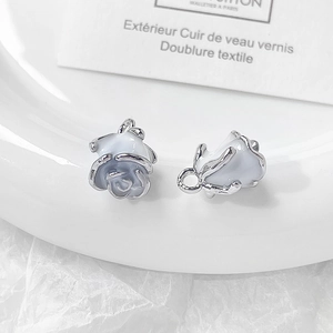 Macro shot of silver edged white and blue enamel rose flower charms for DIY jewelry making
