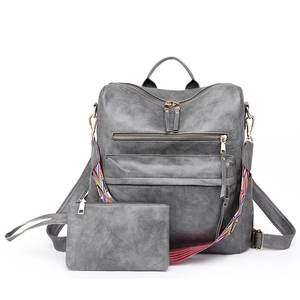 Detail of grey leather backpack set with golden hardware and patterned strap close-up