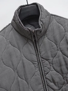 Detail of dark gray wave-quilted jacket featuring high-quality silver metal zipper