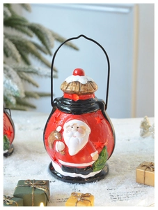 Détail d'une lanterne de Noël rouge en céramique avec Père Noël en relief et anse en métal noir