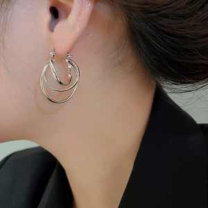 Close-up of triple layered silver hoop earrings worn by a model for a chic look