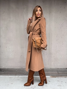 Outdoor shot of a classic camel wool coat with waist tie and notched lapels detail