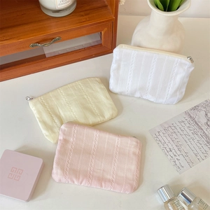 Detailed view of three-piece lace textured cosmetic bags in white, beige and pink tones
