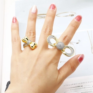 Adjustable gold-plated bow rings with pavé zircon stones on a fashion magazine background
