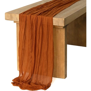 Detail of brown pleated voile table runner draped over a wooden bench for weddings